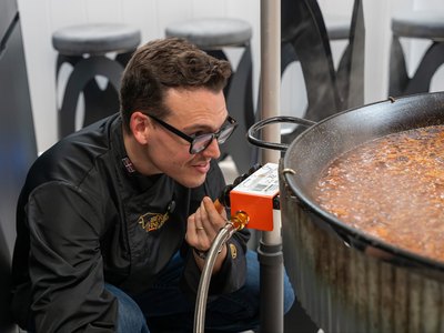 A guest leaning in over the paella as it finishes