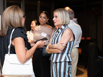 A group of guests talking with drinks and plates in hand