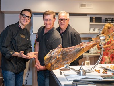 Three of the evening's hosts behind the island with a whole ham, before the carving started