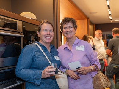Two guests with drinks in hand among the kitchens