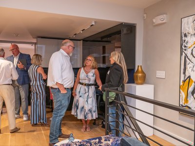Guests in conversation on the upper floor of the showroom, early in the evening